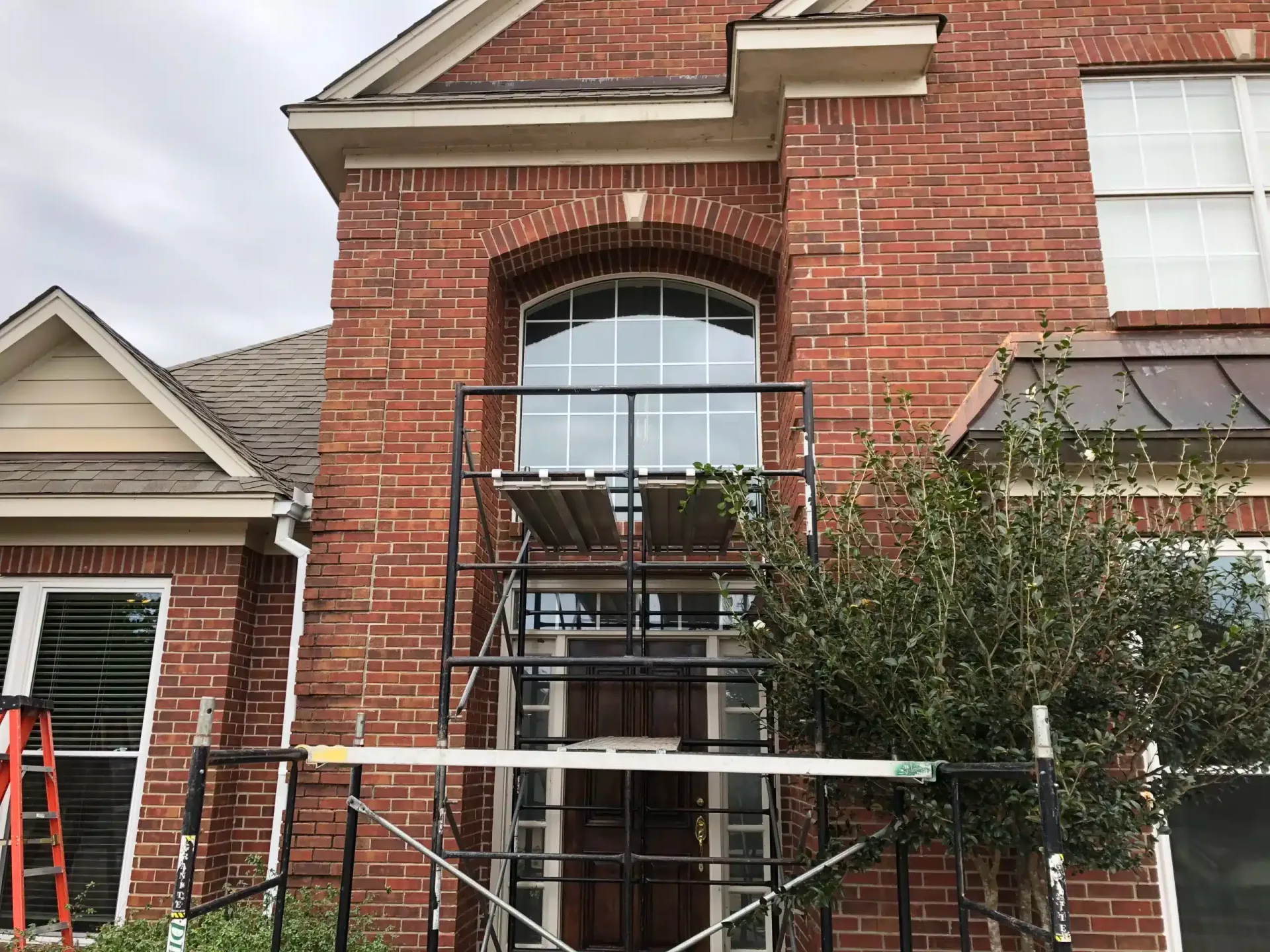 Before: two-story brick home with the old arched window