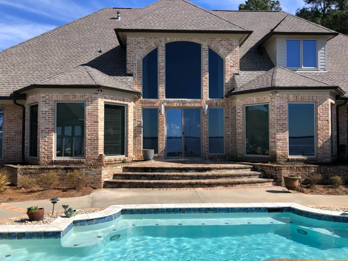 After: brick home with the new tall arched window over the pool