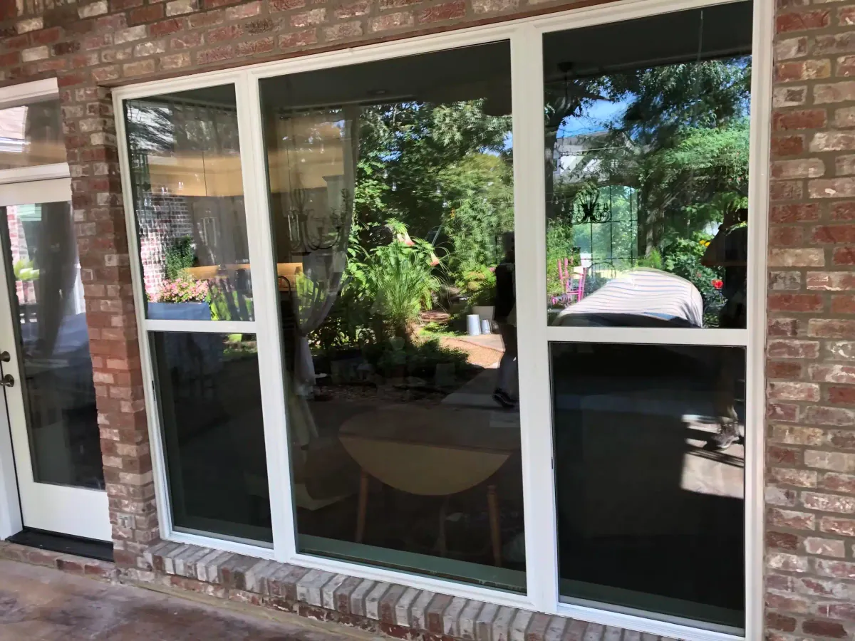 New white replacement window installed in a brick wall beside a covered patio