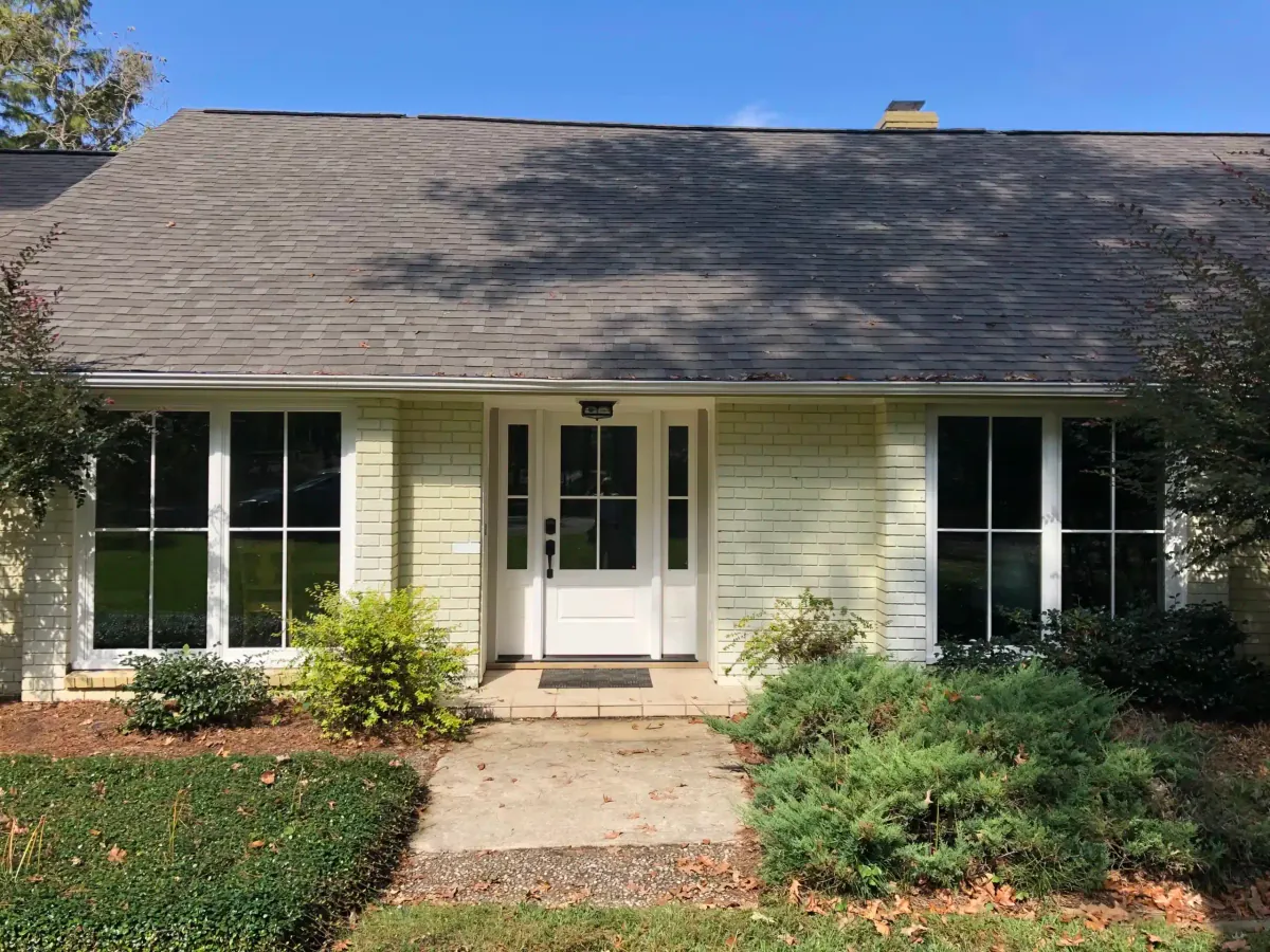 After: front view of the older home with new white windows and entry door