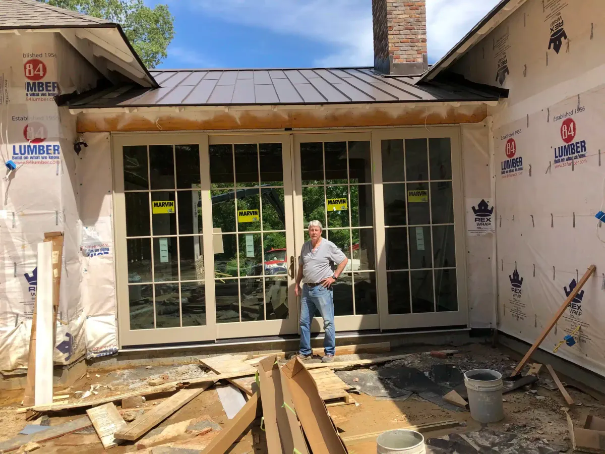 George Fowler standing in front of a newly installed wall of sunroom windows during construction